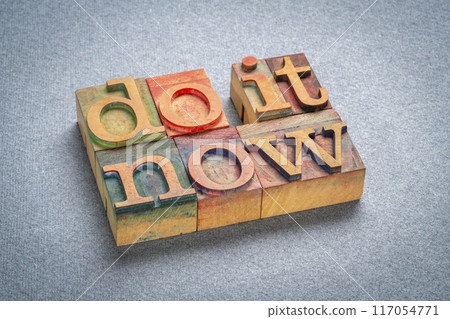do it now - motivational text in retro letterpress wood type stained by color inks, productivity concept 117054771