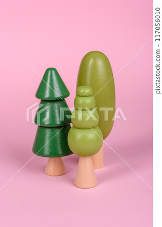 Wooden model of a tree with a green crown and trunk on a pink background 117056010
