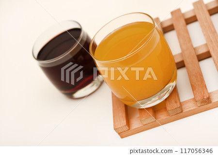 Juice in glass cups on a stand. Cherry and orange juice. 117056346