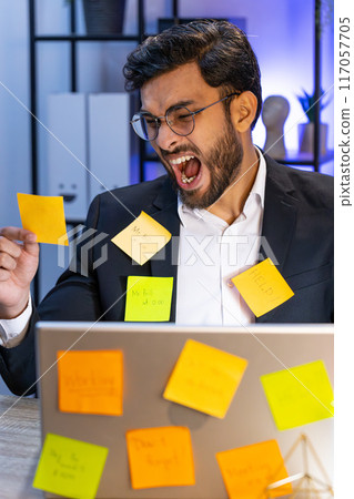 Tired sad exhausted businessman working on laptop at office with many sticker tasks, panic attack 117057705