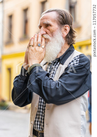 Portrait of senior man praying with closed eyes to God asking for blessing help forgiveness outdoors Portrait of senior man praying with closed eyes to God asking for blessing help forgiveness outdoors 117057732