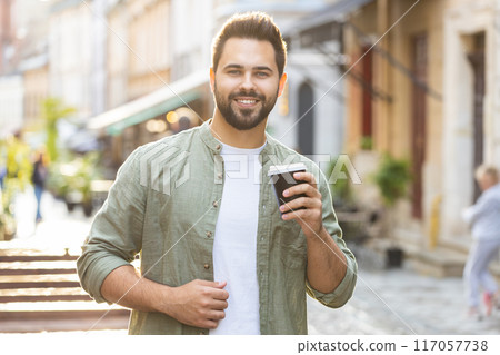 Young man guy enjoying drinking morning coffee hot drink, relaxing, taking a break in city street Young man guy enjoying drinking morning coffee hot drink, relaxing, taking a break in city street 117057738