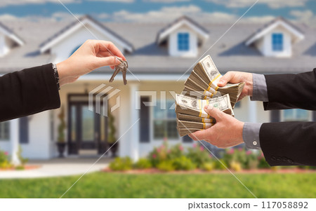 Real Estate Agent Handing Over House Keys for Stacks of Money in Front of New House. 117058892