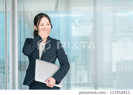 一位年輕的亞洲女商人在辦公大樓前震驚/驚訝地摀住臉（悲傷/裁員/麻煩） 117058915