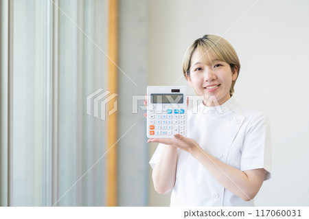 A young female chiropractor with short blonde hair holding a calculator (free hair color, work in your own way, work environment) A young female chiropractor with short blonde hair holding a calculator (free hair color, work in your own way, work environment) 117060031
