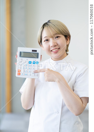 一位年輕的金髮短髮女脊椎按摩師拿著計算器（自由髮色，以自己的方式工作，工作環境） 117060038