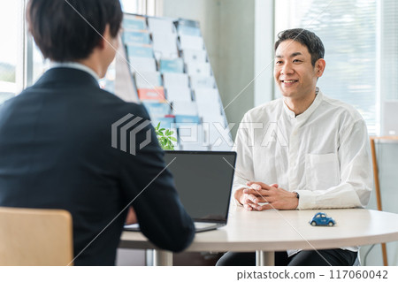A middle-aged man who came to consult about car insurance and a male businessman who is serving him A middle-aged man who came to consult about car insurance and a male businessman who is serving him 117060042