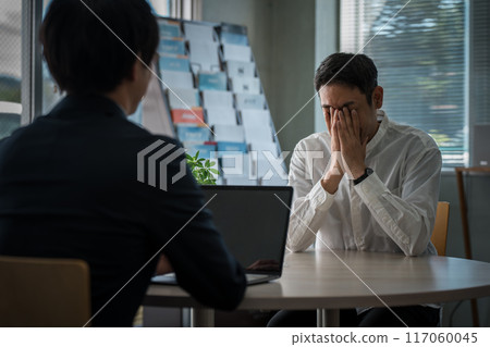 A middle-aged man who came to consult about car insurance and a male businessman who is serving him 117060045