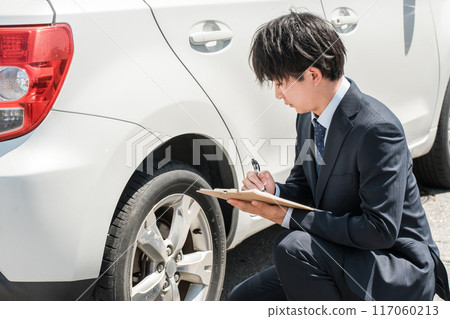 Male salesman/appraiser staff using a checklist to assess and estimate a car Male salesman/appraiser staff using a checklist to assess and estimate a car 117060213