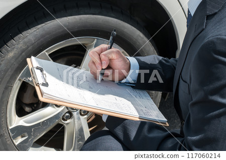 Salesman/appraiser using a checklist to assess and estimate a car Salesman/appraiser using a checklist to assess and estimate a car 117060214