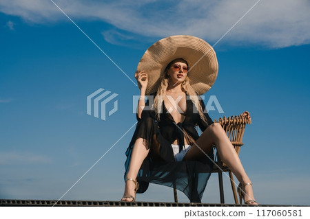 Woman in Wide-Brimmed Hat Sitting on a Chair 117060581