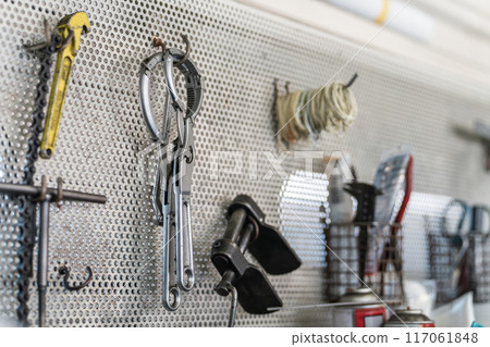 Wall-mounted tools, punched panels, and tool shelves in a repair shop 117061848