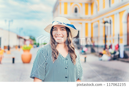 Lifestyle of happy traveler woman in a tourist square. Portrait of smiling tourist girl on the streets of Granada, Nicaragua 117062235