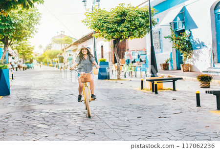 Young tourist woman riding a bicycle on the streets of Granada, Nicaragua. Happy tourist girl riding a bicycle on Calzada street 117062236