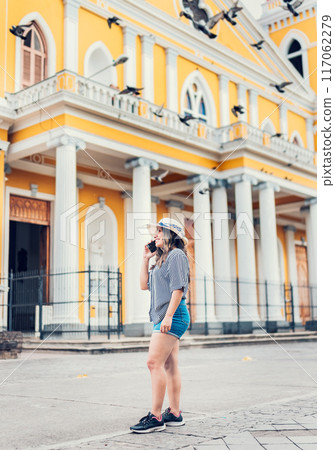 Female tourist talking on cell phone in the square. Granada, Nicaragua. Happy travel woman calling on the phone in on the street 117062279