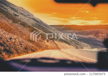 Driving a car on a mountain road during sunset. The way to Nordkapp (North Cape). Norway Driving a car on a mountain road during sunset. The way to Nordkapp (North Cape). Norway 117065073