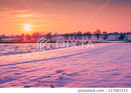 Evening in a winter village. Plowed field covered with snow 117065552