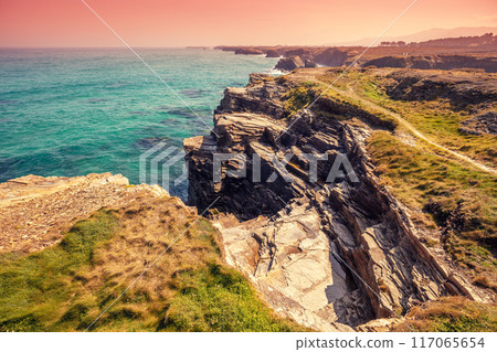 Seascape on a sunny day. Rocky sea coast on the Beach Playa de Las Catedrales in Ribadeo, Galicia, Spain 117065654