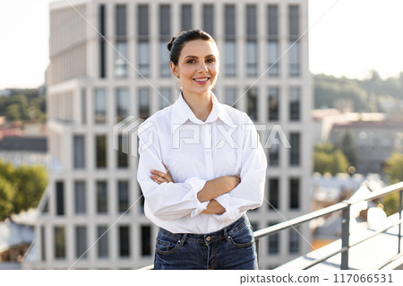 Confident businesswoman standing with arms crossed on rooftop Confident businesswoman standing with arms crossed on rooftop 117066531