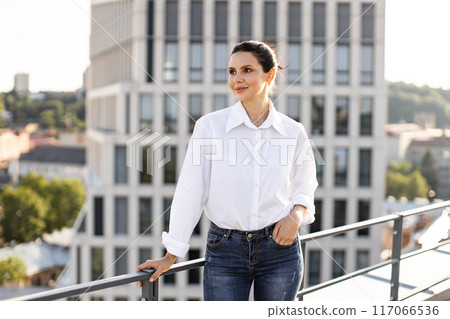 Confident woman standing on rooftop with city skyline background 117066536