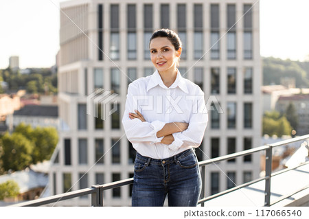 Confident woman standing on rooftop with cityscape background Confident woman standing on rooftop with cityscape background 117066540