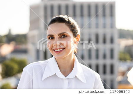 Smiling woman in white shirt with urban background Smiling woman in white shirt with urban background 117066543