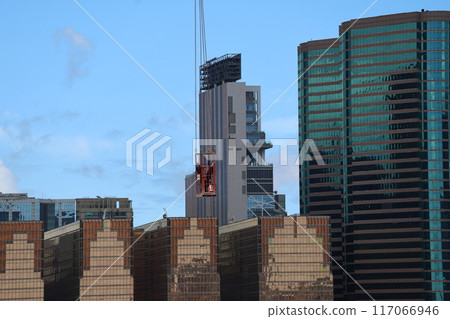 藍天和摩天大樓大城市天際線上懸掛著起重機滑輪籠的景觀 藍天和摩天大樓大城市天際線上懸掛著起重機滑輪籠的景觀 117066946