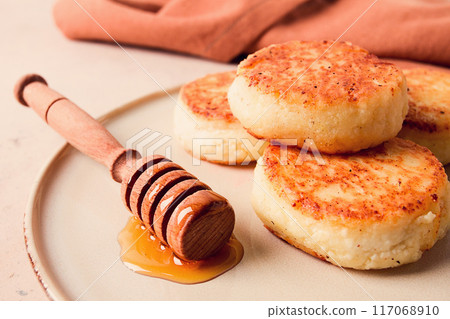Cottage cheese pancakes, with honey, close-up, on a beige table, selective focus, no people, Cottage cheese pancakes, with honey, close-up, on a beige table, selective focus, no people, 117068910