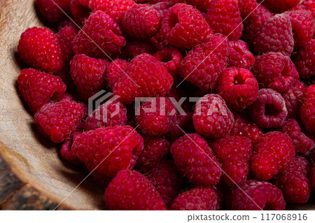 fresh raspberries in a wooden bowl, food background, concept, food styling, on a dark table, top view, no people fresh raspberries in a wooden bowl, food background, concept, food styling, on a dark table, top view, no people 117068916