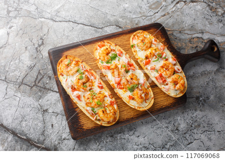 Mozzarella shrimps open sandwiches baked on Italian garlic bread close-up on a wooden board. Horizontal top view 117069068