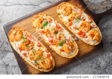 Shrimp Scampi Garlic Bread sandwiches with mozzarella, tomatoes and parsley closeup on the wooden board. Horizontal top view Shrimp Scampi Garlic Bread sandwiches with mozzarella, tomatoes and parsley closeup on the wooden board. Horizontal top view 117069070