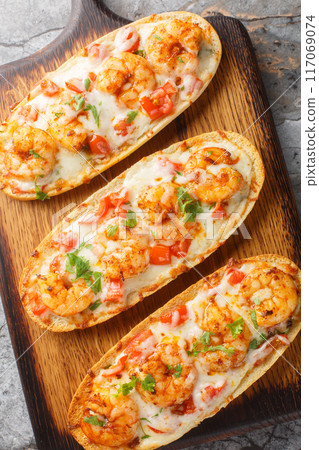 Cheesy Shrimp Garlic Bread with herbs and tomato closeup on the wooden board. Vertical top view 117069074
