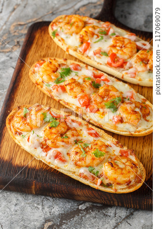 Hot baked sandwiches with shrimps, cheese, garlic and tomatoes close-up on a wooden board. Vertical Hot baked sandwiches with shrimps, cheese, garlic and tomatoes close-up on a wooden board. Vertical 117069079