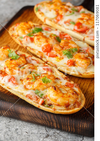 Cheesy Shrimp Garlic Bread with herbs and tomato closeup on the wooden board. Vertical 117069081
