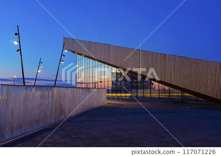 Modern architectural structure with angular lines and reflective glass surfaces is captured during evening in new Tallinn Cruise Harbour 117071226
