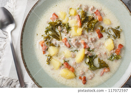 Italian traditional soup Zuppa Toscana with sausages, kale, potatoes and bacon close-up in a plate. Horizontal top view 117072597