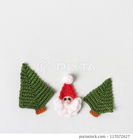 Christmas composition of knitted green Christmas trees and Santa Claus on gray background. Winter knitting creativity. Holiday concept, gifts, greeting card 117072627
