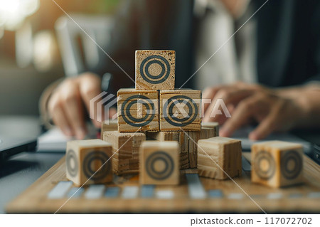 High resolution image, businesswoman hand stacking wood blocks with target icon on office desk, laptop 117072702