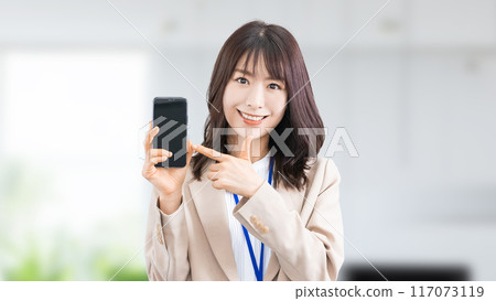 Smiling Japanese businesswoman pointing at smartphone 117073119