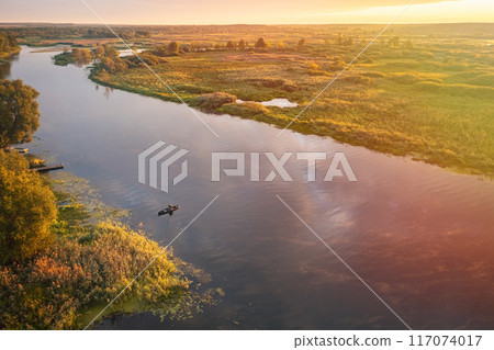 A serene river landscape at sunset, featuring lush greenery and stunning water reflections A serene river landscape at sunset, featuring lush greenery and stunning water reflections 117074017