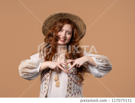 Smiling ginger woman showing sign of shape heart. Positive lady on beige. Love. Women health, volunteering, charity donation, gratitude symbol, flirting concept 117075531