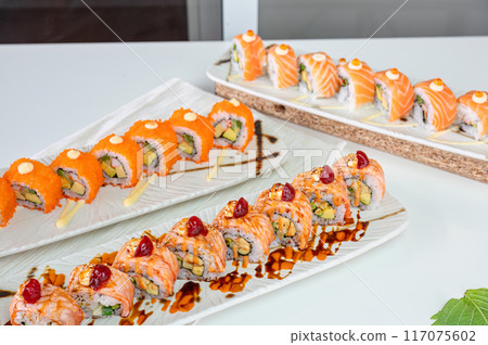 Ceramic tray with variety of salmon sushi roll with vegetables, appetizing japanese meal Ceramic tray with variety of salmon sushi roll with vegetables, appetizing japanese meal 117075602