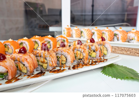 Ceramic tray with variety of salmon sushi roll with vegetables, appetizing japanese meal 117075603