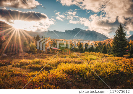 Sunrise shining over wooden huts with rocky mountains in autumn forest at Assiniboine provincial park, Canada 117075612