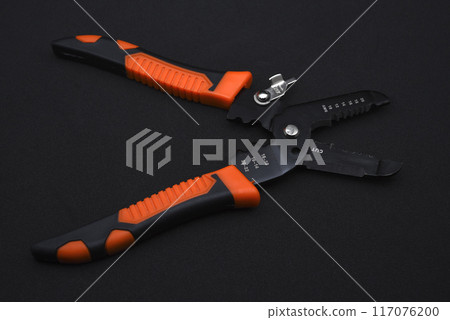 Insulation puller or stripper is an electrical installation tool on a black background. Insulation puller or stripper is an electrical installation tool on a black background. 117076200
