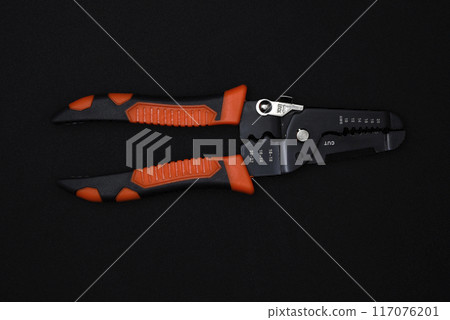Insulation puller or stripper is an electrical installation tool on a black background. Insulation puller or stripper is an electrical installation tool on a black background. 117076201
