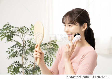 A woman using a facial beauty device while looking in the mirror A woman using a facial beauty device while looking in the mirror 117076389