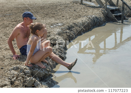 Happy family child girl and dad on mud geyser resort with therapeutic mud outdoor 117077223