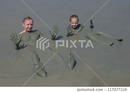 Happy people on mud geyser resort with therapeutic mud outdoor.  117077226