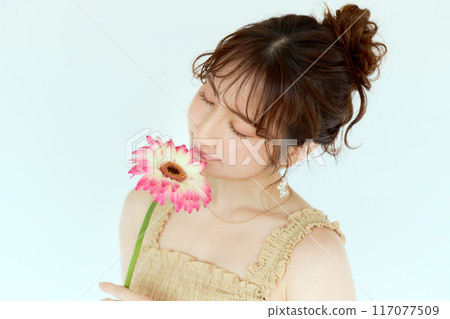Portrait of a woman holding a gerbera Portrait of a woman holding a gerbera 117077509